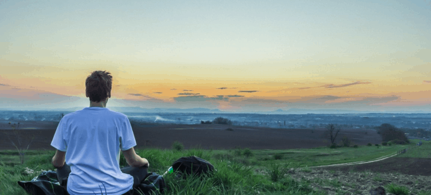 Man sitting in field watching the sunset